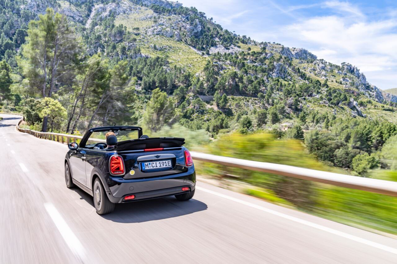 MINI Cabrio 2024 en version SE de trois-quart arrière en dynamique sur la route.